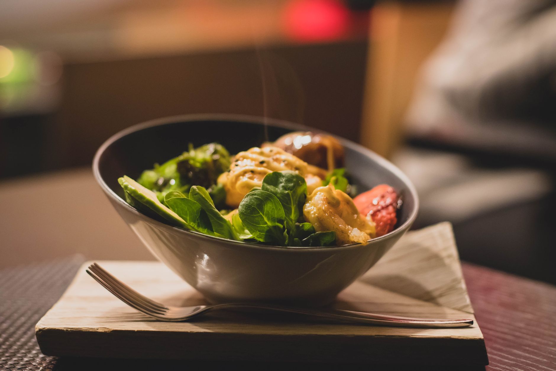 Frische Salatschale mit Hähnchen und Kräutern auf einem Holzbrett